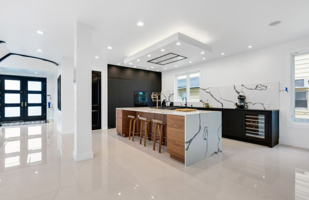 Large remodeled kitchen with marble island, dark cabinetry, and recessed lighting.