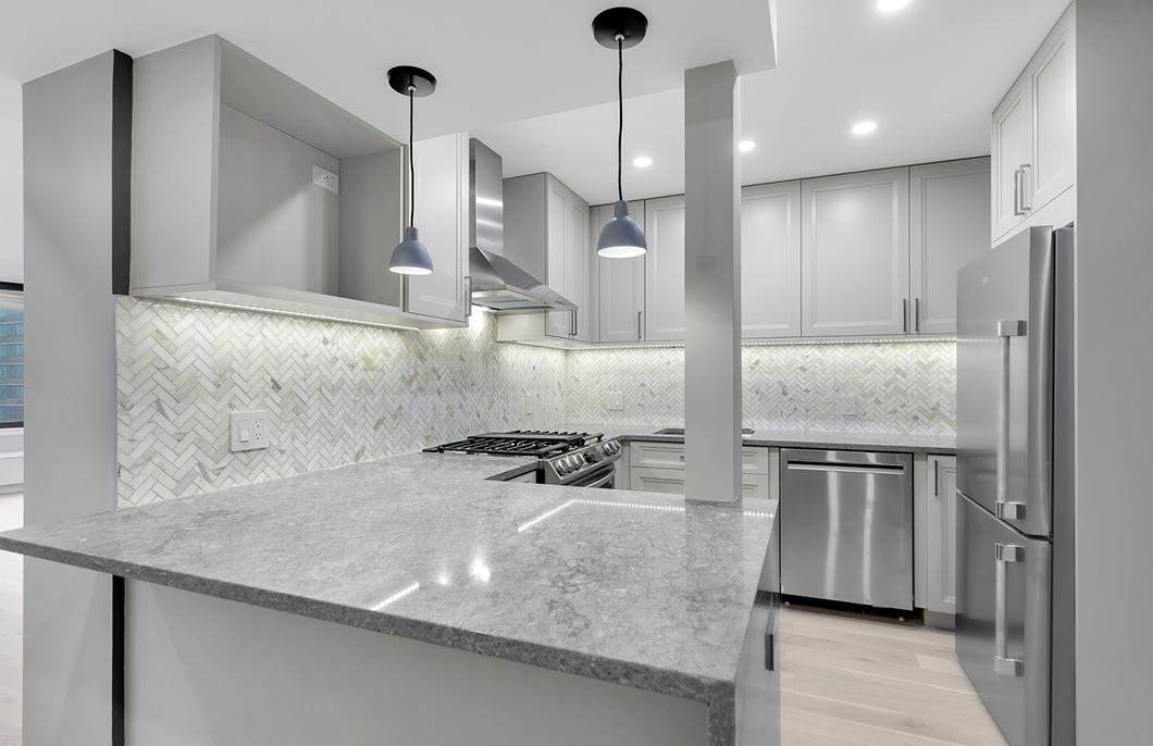Remodeled kitchen with pendant and recessed lighting and white and gray tones