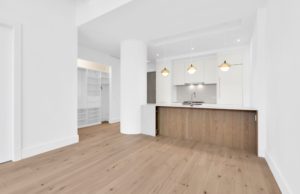 Remodeled loft with wood floors, white walls, and pendant fixtured lighting over the kitchen built-in area