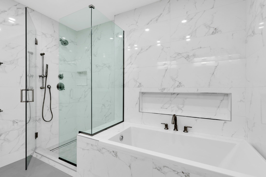 Remodeled bathroom with white tile walls and separate tub and glass-enclosed shower.
