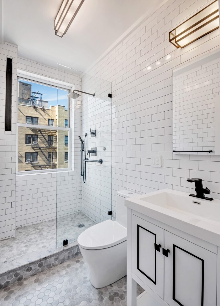 Remodeled bathroom with white subway tile walls and glass-enclosed shower.