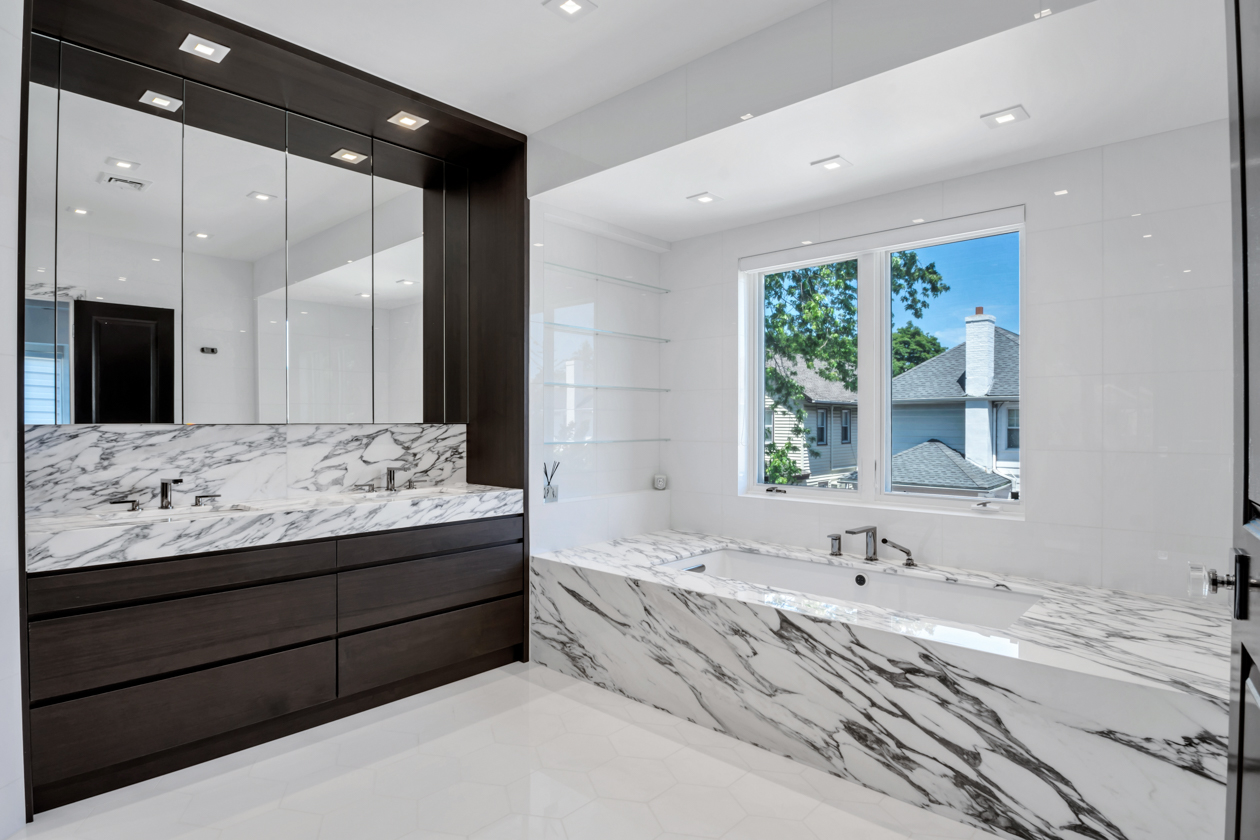 Remodeled bathroom with dark cabinetry and marble bath.