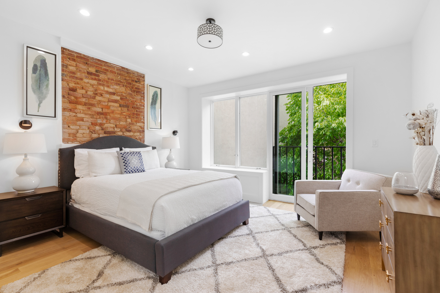 Remodeled bedroom with sliding glass doors and accent brick wall above headboard of bed.