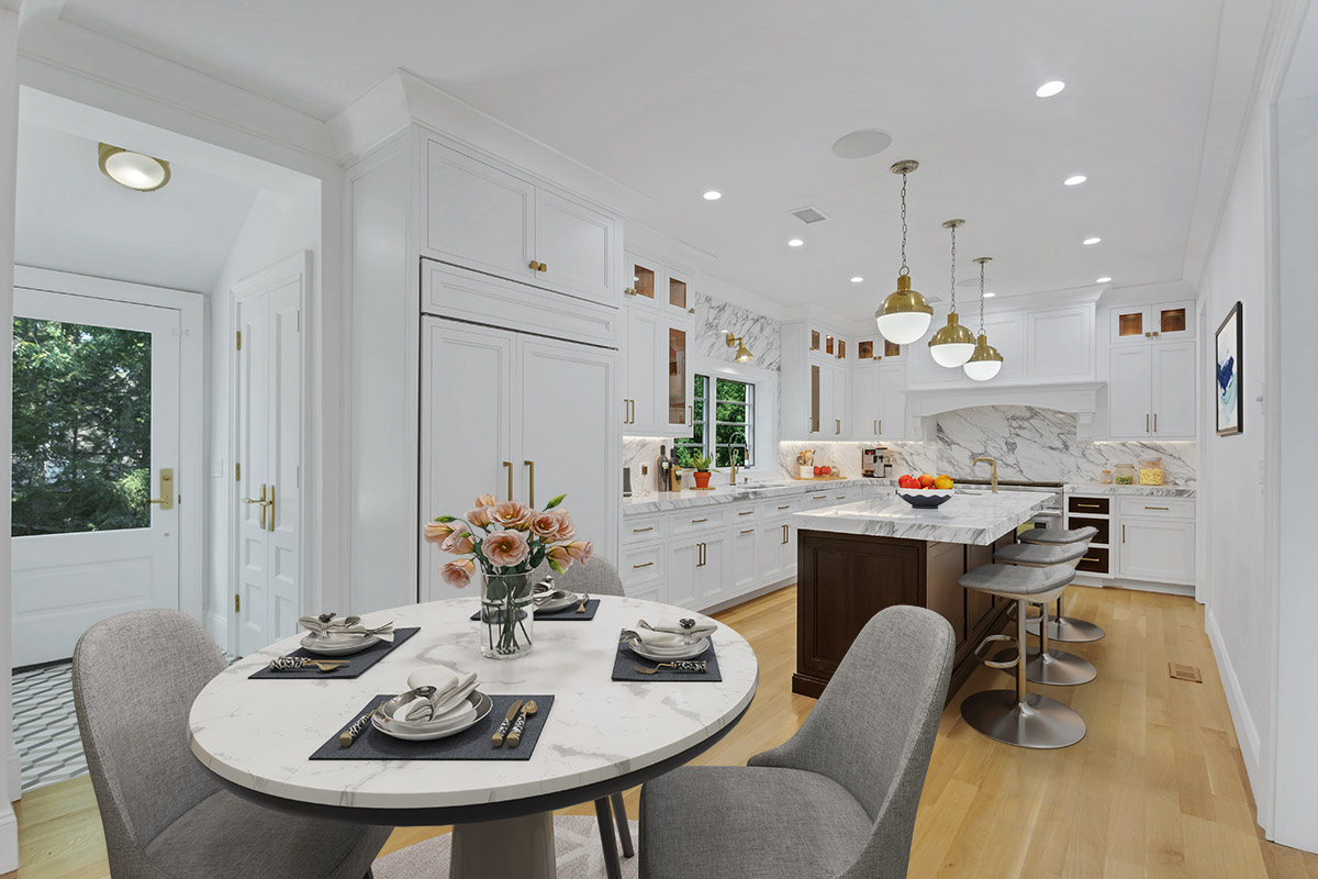 Remodeled kitchen and dining area with round marble-top table, white cabinets, and large island.