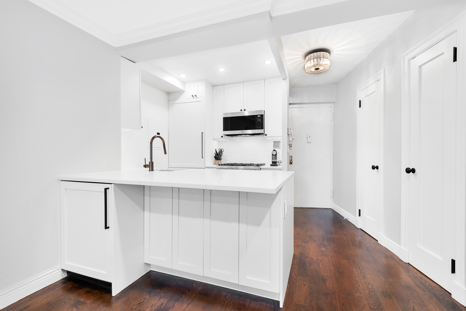Remodeled kitchen with white countertops and cabinetry.