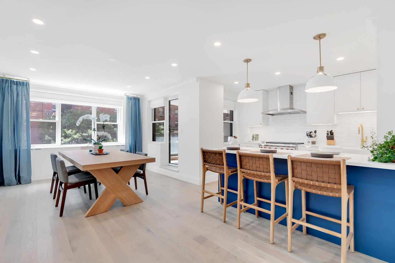 Remodeled kitchen with blue island, white counters, recessed lighting, and large dining area.