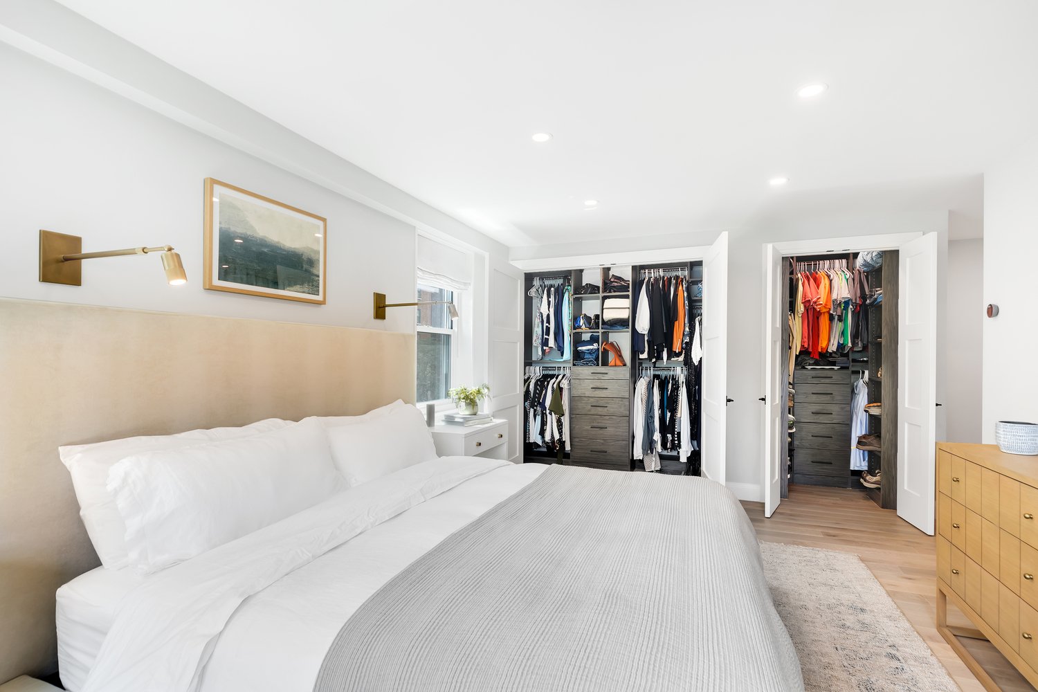 Remodeled bedroom with light wood floors, large closets, and white walls.