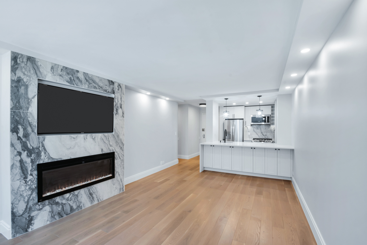 Interior remodel with wood flooring and white walls and built-in fireplace.