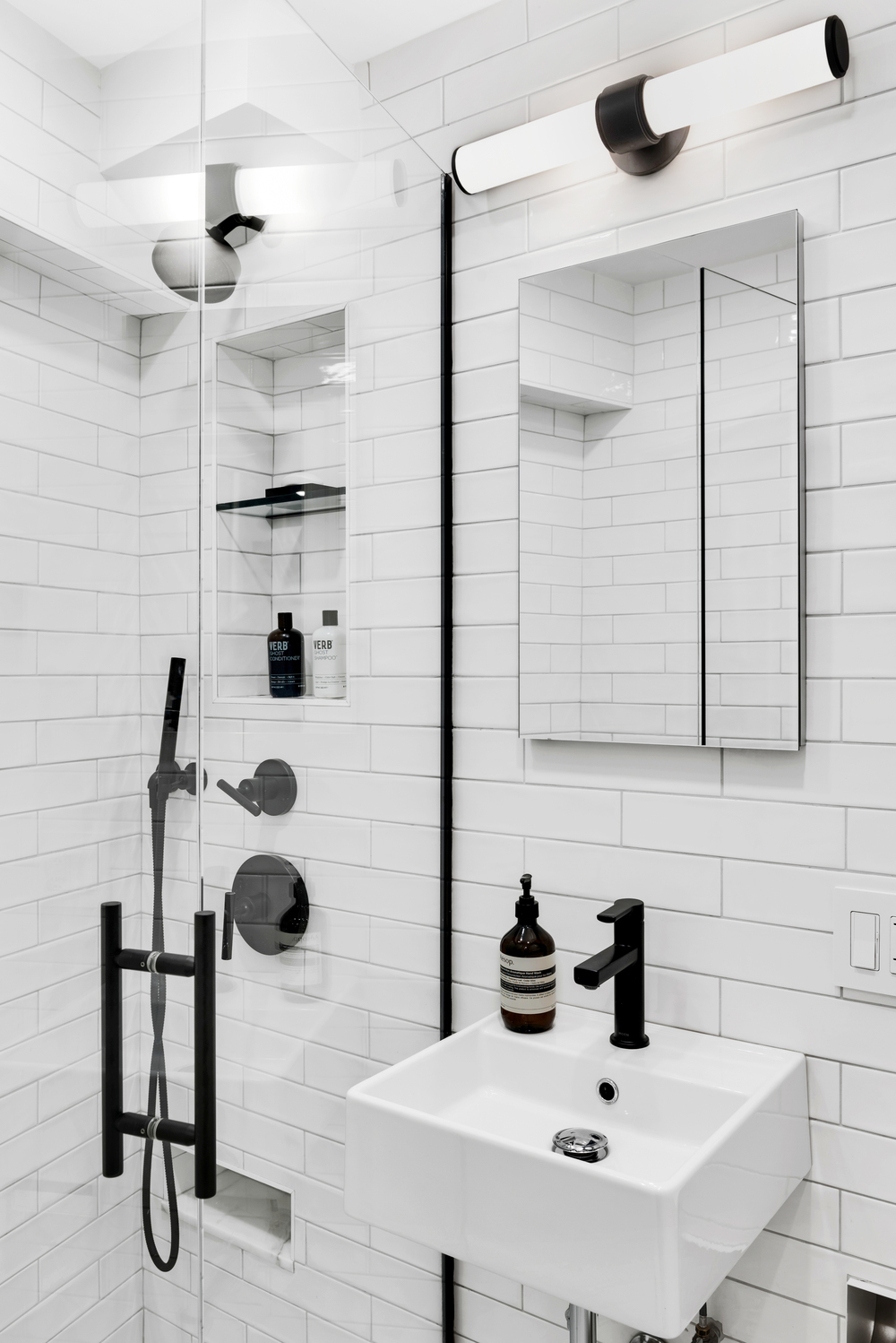 Bathroom remodel with glass shower doors, white subway tile, and matte black fixtures.