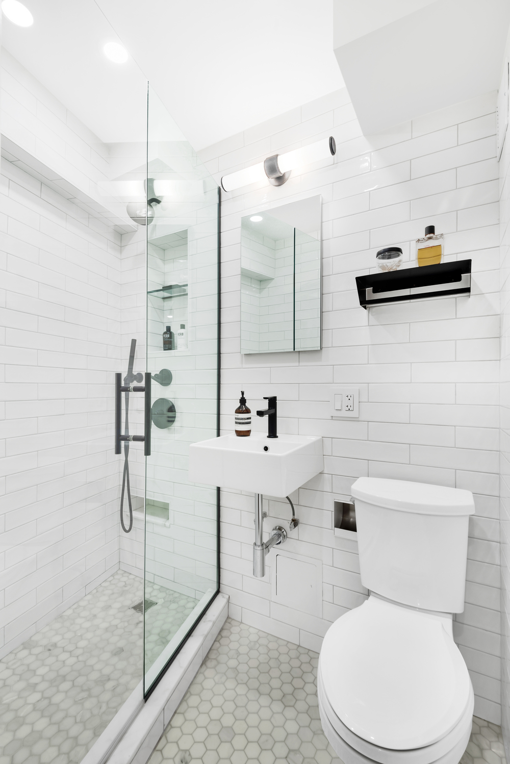 Bathroom remodel with glass shower doors and white subway tiled walls.