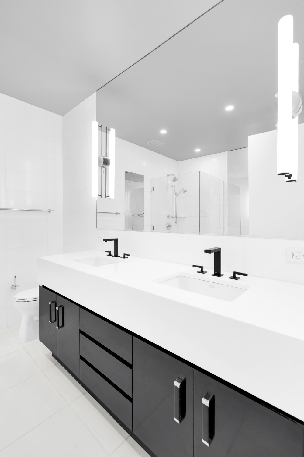 remodeled bathroom with white sinks and dark base.