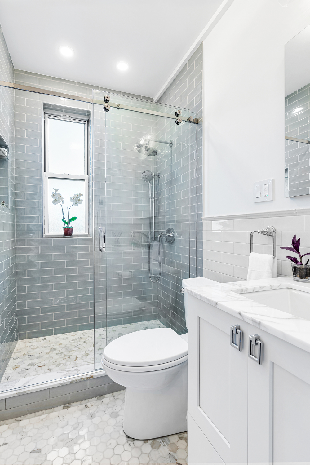 Remodeled bathroom with glass shower and white vanity