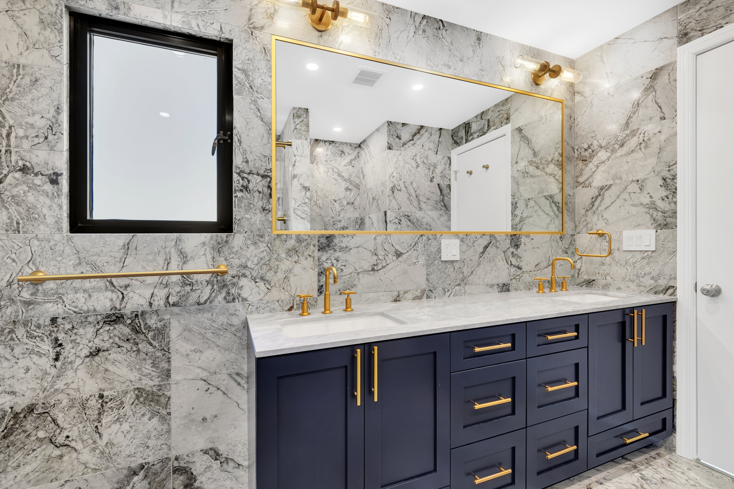 Remodeled bathroom with dark blue cabinetry and gold trim